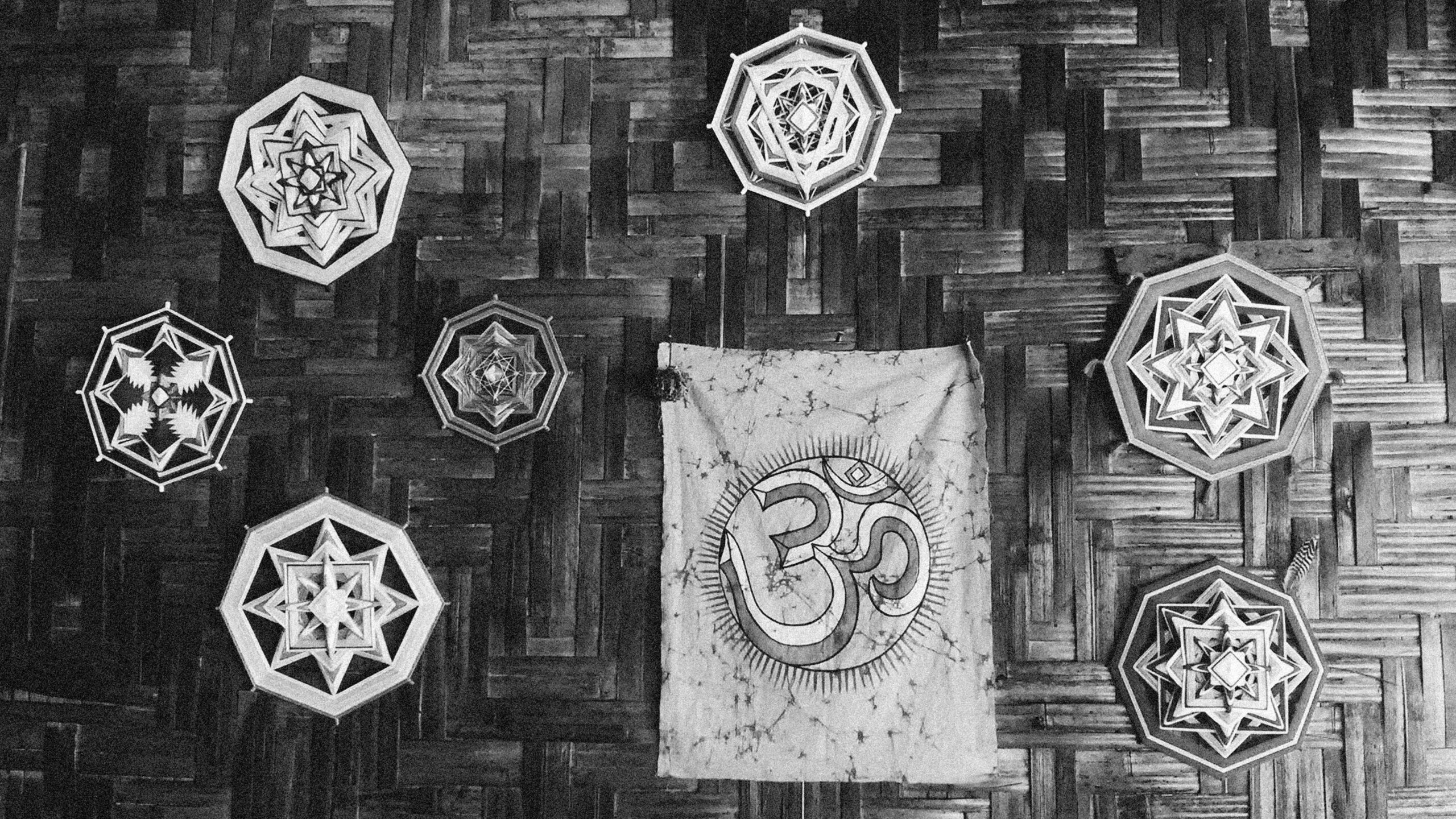 Black and white image of geometric wall art and Om symbol on wooden background.